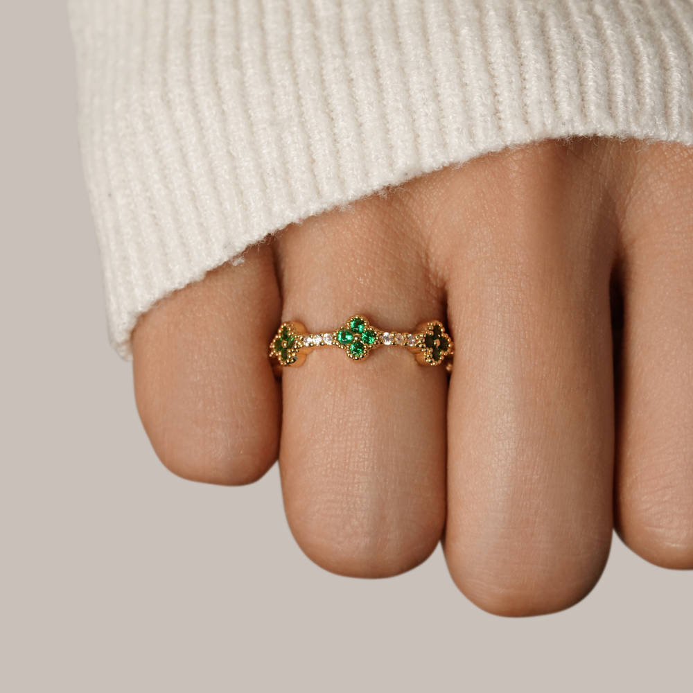 Annika – Gold ring with floral details and emerald accents.